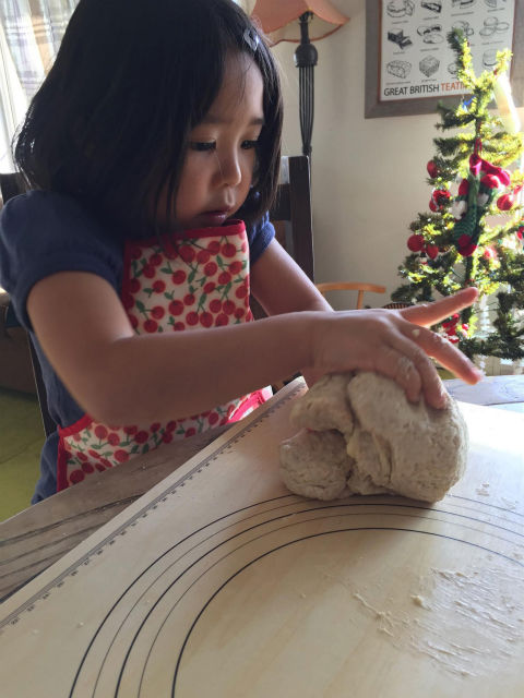 子どもがパンの生地をこねる