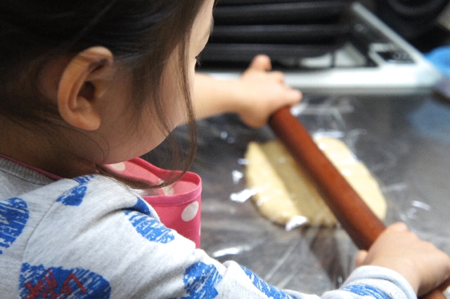 綿棒でパン生地を伸ばす子ども