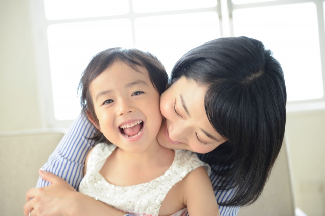 子どもに後ろからハグをするママ