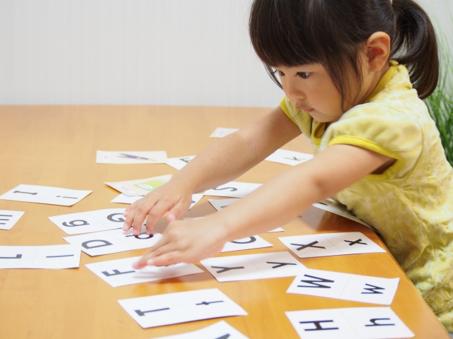アルファベットのカードで遊ぶ女の子