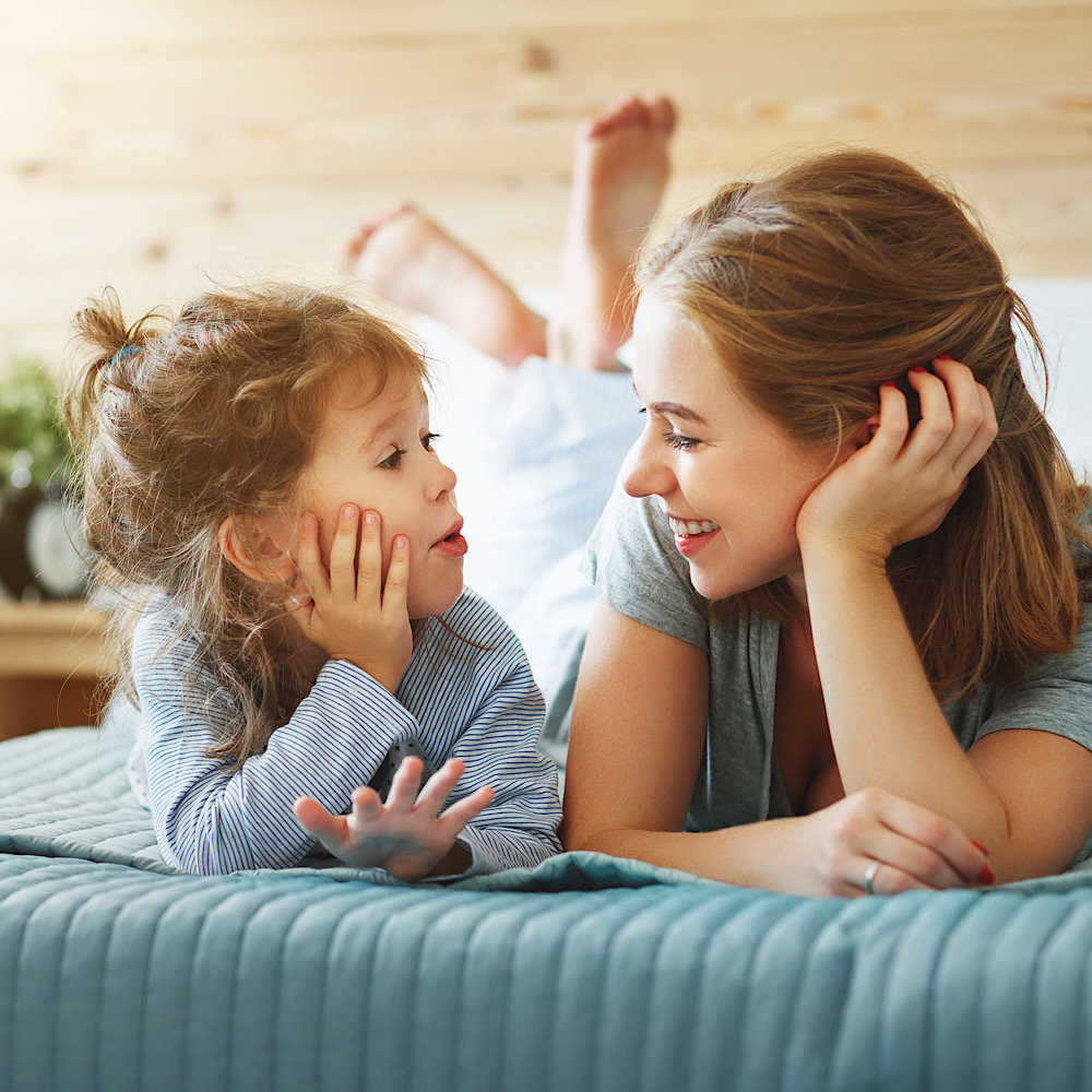 Happy family mother and child daughter play and laughing in bed